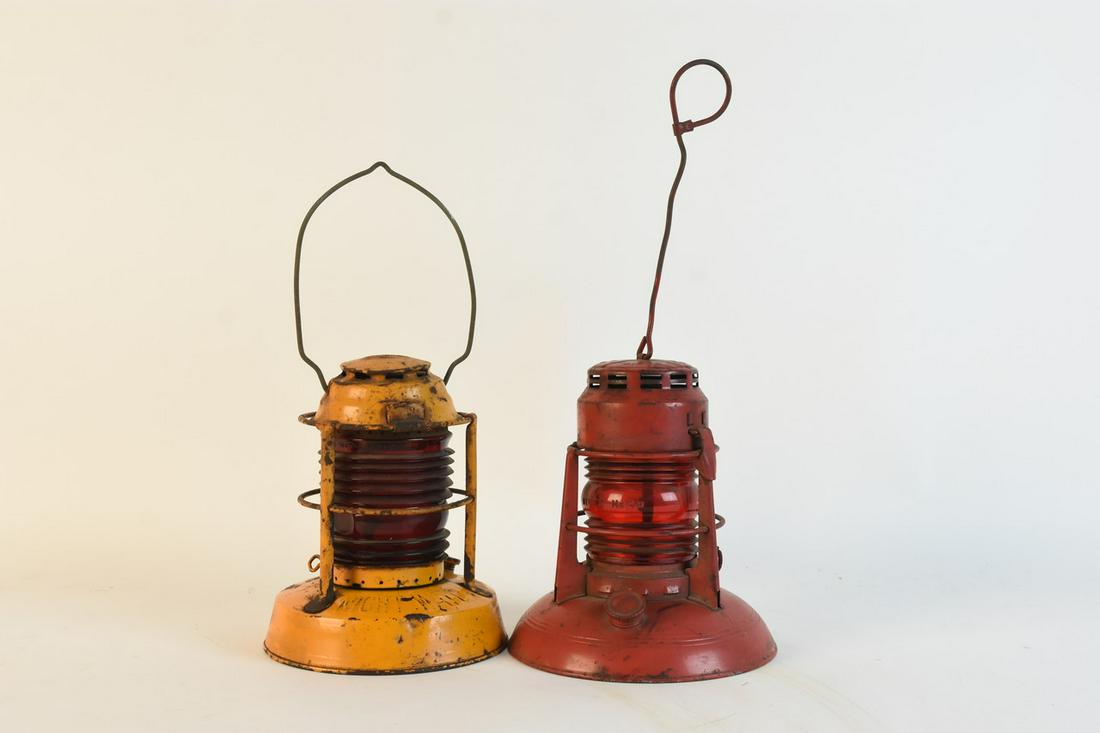 Pair of Dietz Lanterns: A pair of Dietz lanterns with red glass globes. Includes a yellow "Night Watch" railroad lantern and a red no. 40 Traffic Gard lantern. The "Night Watch" lantern measures approx. 13.5" H x 7" W with h