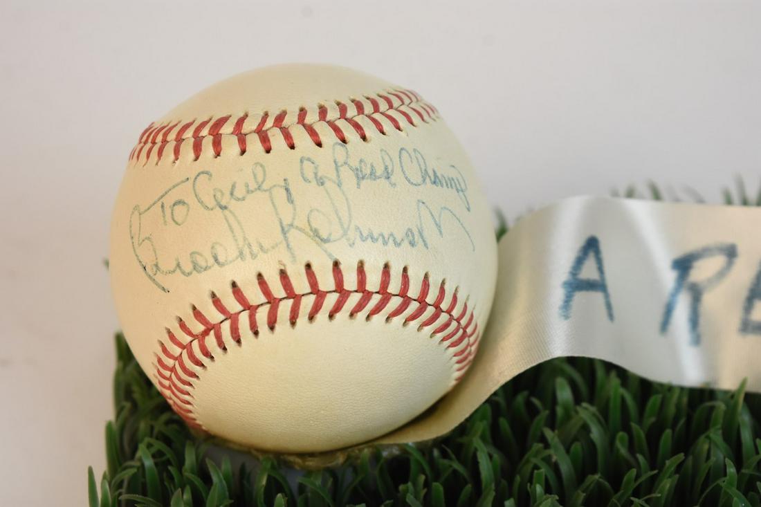 Brooks Robinson Signed Baseball: A Wilson baseball signed along its sweet spot by Brooks Robinson in blue ink with a personalized message that reads "To Cecil, a Real Champ." The ball is affixed to a piece of astroturf with a ribbon 