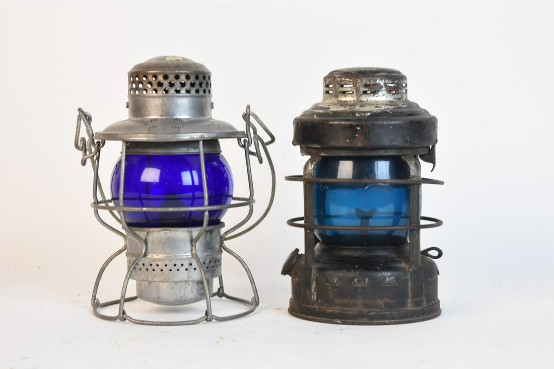 Railroad Lanterns with Blue Globes: A pair of railroad signal lights with blue glass globes. Includes one Pennsylvania Railroad lantern marked Armspear Mfg. Co C. New York, 1925; and one with blue glass marked "Dietz Little Wizard." Con