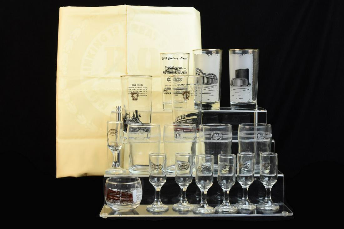 Railroad Glassware and B&O Tablecloth: A selection of (16) drinking glasses and a Baltimore and Ohio tablecloth. Includes (4) commemorative Pennsylvania Railroad highball glasses; one New York Central System commemorative highball glass; (