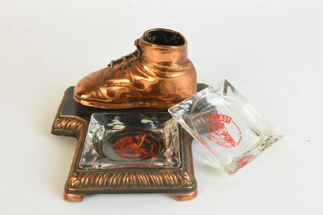 Bron-Shoe Ashtray Holder w/ Frisch's Ashtrays: A pair of vintage Frisch's Big Boy glass ashtrays with a bronzed Bron-Shoe Co. baby shoe ashtray holder. Ashtray holder is marked to its underside and measures approx. 4.5" H x 7" W x 7.25" D. Loss of