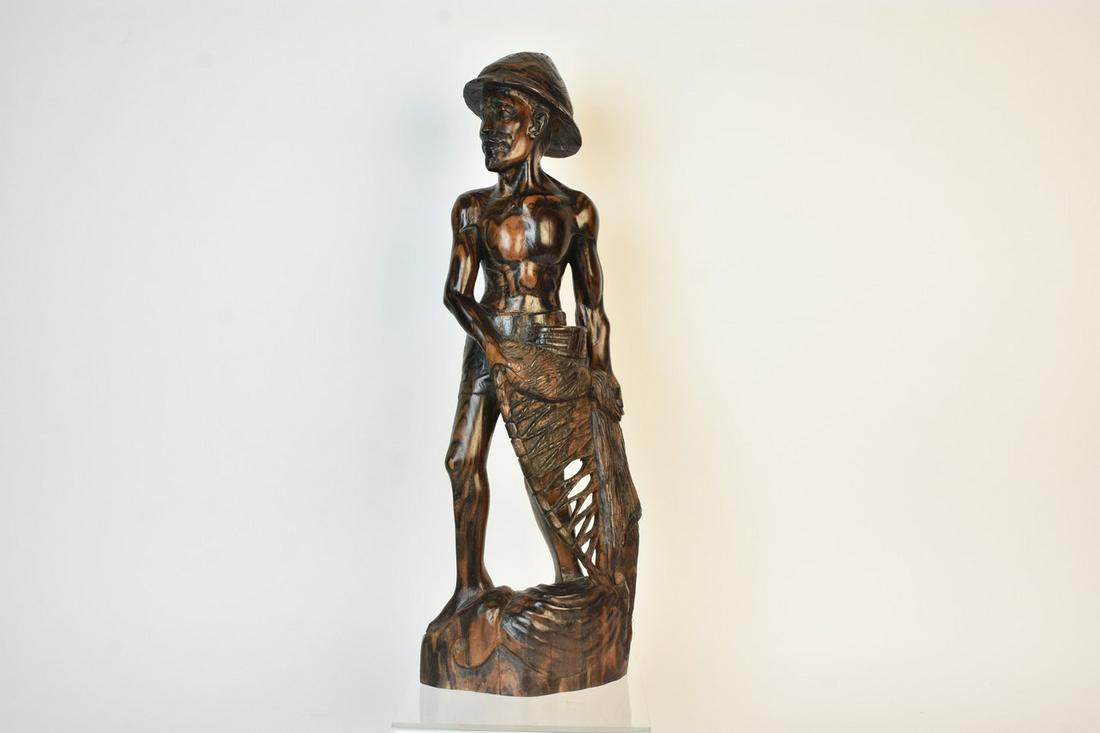 Balinese Carved Fisherman: A hardwood hand carved statue of a fisherman likely made in the Indonesian island of Bali. Unsigned. Measures approx. 22.5" H x 7.5" W x 4.75" D. Please Note: Scheerer McCulloch Auctioneer only ships 