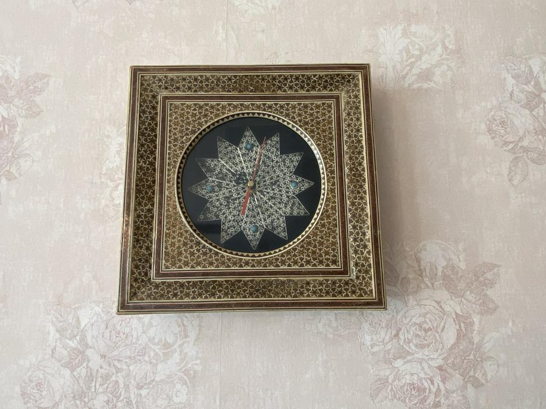 Persian Inlaid Clock: A battery-operated clock encompassed by an ornate inlaid frame. Measures approx. 10.25" W x 10.5" H. Light discoloration and wear. Please Note: Scheerer McCulloch Auctioneer only ships a limited numbe