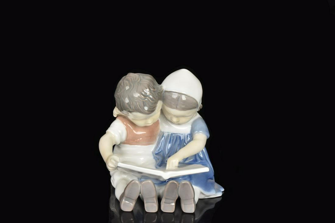 Bing & Grondahl Porcelain Figurine: A Bing & Grondahl porcelain figurine #1567 depicting two children reading. Marked to its underside. Dust residue. Measures approx. 4" H. Please Note: Scheerer McCulloch Auctioneer only ships a limited