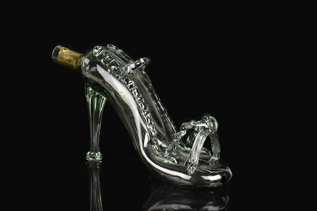 Glass Slipper Decanter: A glass slipper decanter depicting a stylish high heeled shoe with a spout to its back. No maker's mark. Measures approx. 7" H x 9" W x 3.25" D. Discoloration to paper around spout; no lid/cork. Pleas