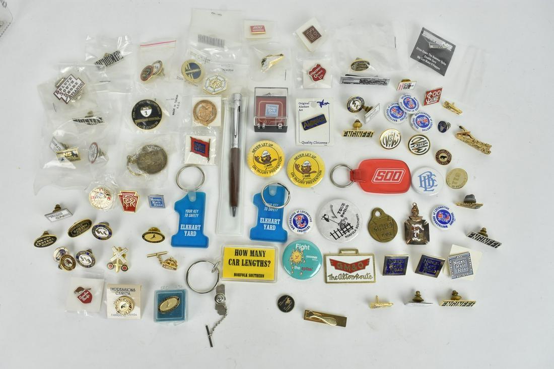 Railroad Pins and Keychains: A collection of railroad memorabilia featuring enameled pins, metal pins, & metal button pinbacks. Also included are various keychains. Condition varies- older pieces showing some surface wear and dis