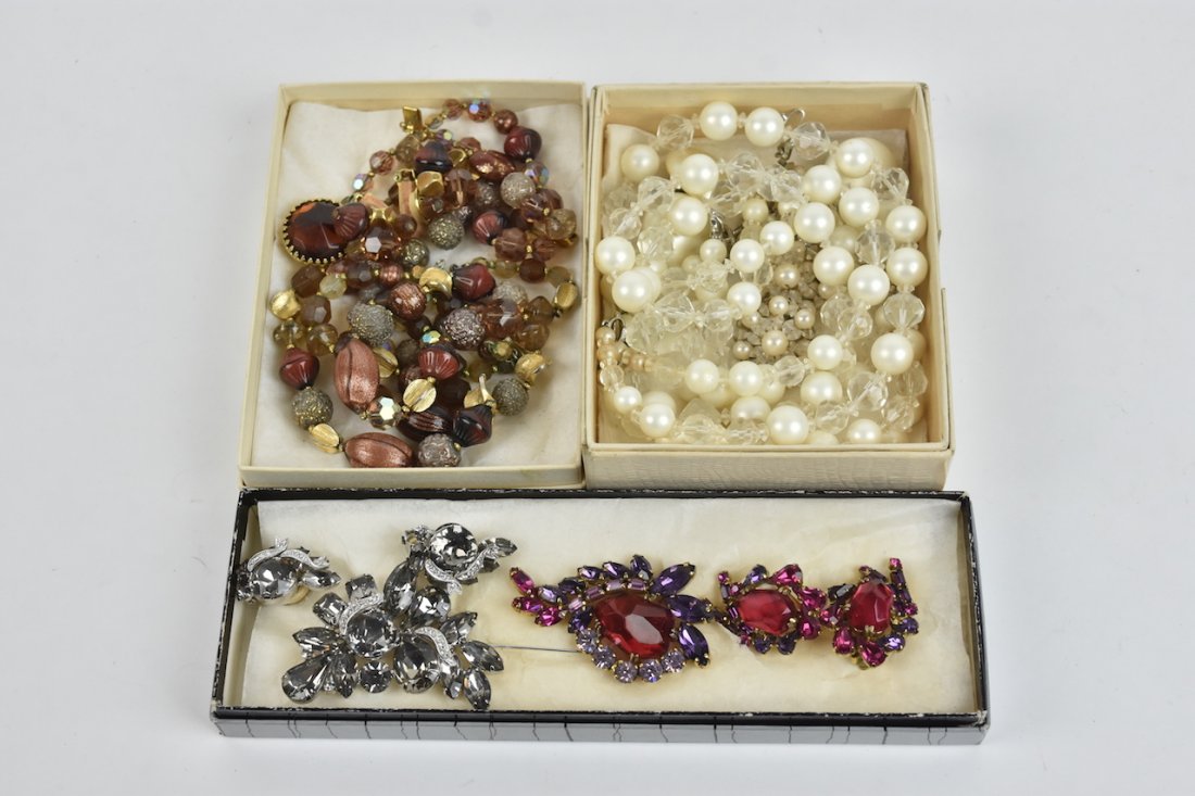 Weiss, Marvella, Carnegie Costume Jewelry: (2) Weiss 2-piece sets. 1-Red/purple/lilac paste gems in a gold tone setting, brooch and clip earrings, 1-Smokey silver in silver tone, brooch and clip earring set. (1) Marvella 3-piece set in faux pe