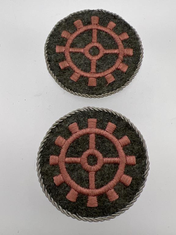 WW II German Military Trade Badges - Two: Two Original Technical Artisans Trade Sleeve Badges. Grey/green wool embroidered with insignia and trimmed in gray twisted piping. Piping looks to be hand stitched. Nice original examples. Lot of 2.