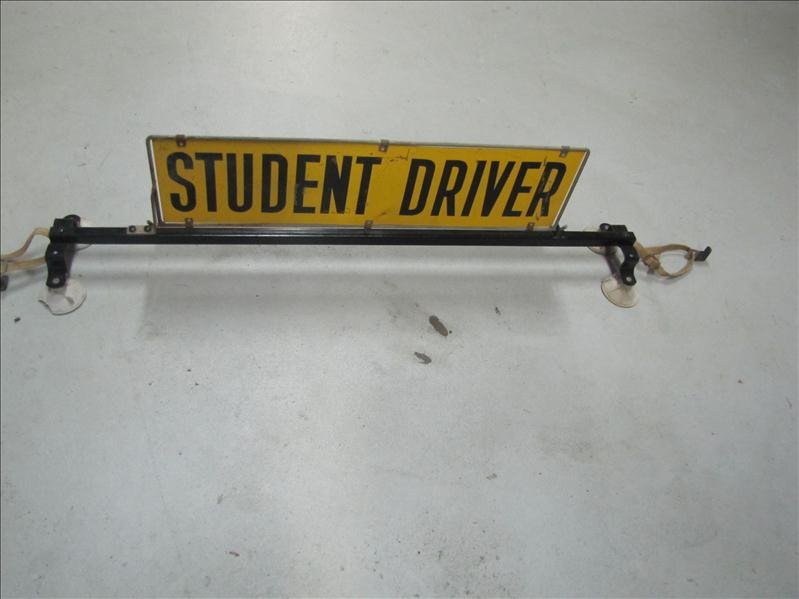Student Driver Roof Mount Sign: Student Driver Roof Mount Sign Yellow with black lettering with black metal stand. Has 4 suction cups with a hook strap on each side. Measures: 28" long x 7.5" high, the rack is 42" long.