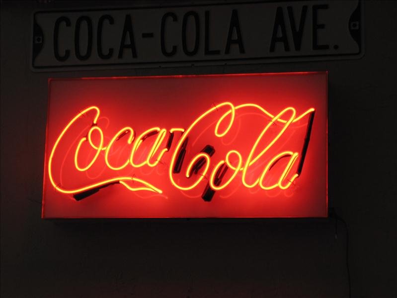 Coca Cola Neon Wall Sign: Coca Cola Neon Wall Sign This is electric powered with pull string on/off cord. The neon lights are mounted on a white box type frame. This measures 24" long x 12.25" tall. This was a custom made piec