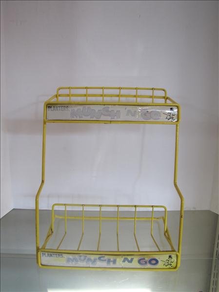 Planters Peanuts Advertising Rack: Planters Peanuts Advertising Rack This rack has to front advertising facings: "PLANTERS MUNCH 'N GO" with the Planters Peanut man. This is painted metal with two shelves. This measures 14.5" tall x 12