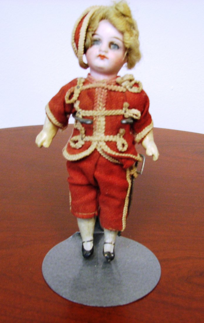 Boy doll with sword: Original clothes with original sword and cap. Bisque head, painted lips, brows, lashes. Closed mouth, Damage to both eyes, mohair hair, composition body. Back of neck is marked but to faint to make ou