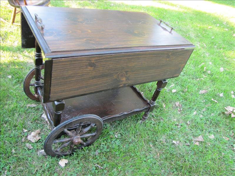 Wooden Wheeled Tea Cart: Wooden Wheeled Tea Cart This has two fold out leafs and is wheeled. There is a lower shelf area. This has a handle at each end for ease of transport. This measures 36" long with leaves, 34" wide x 28.