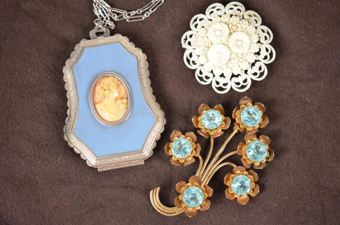 (3) Pcs. Costume Jewelry: Included is a ladies makeup compact on a chain, a brass finish broach pin with synthetic blue stones, and a plastic construction pin with flower motif.