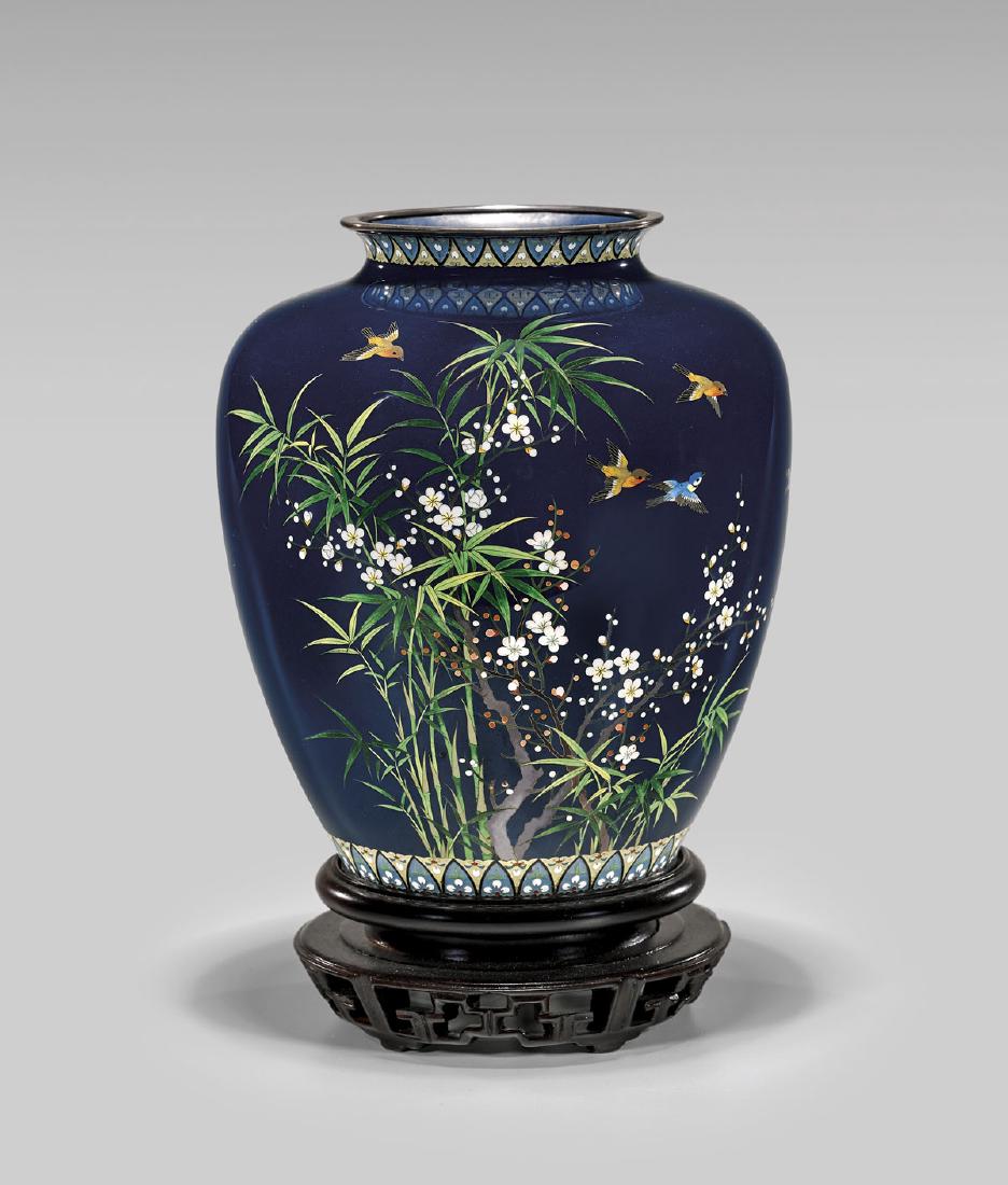 JAPANESE INABA CLOISONNÉ ENAMEL VASE: Old Japanese cloisonné enamel vase by Inaba; the wide-shouldered, tapered form with design of orange and blue birds flying above flowering prunus and bamboo stalks, on dark blue ground; the nec