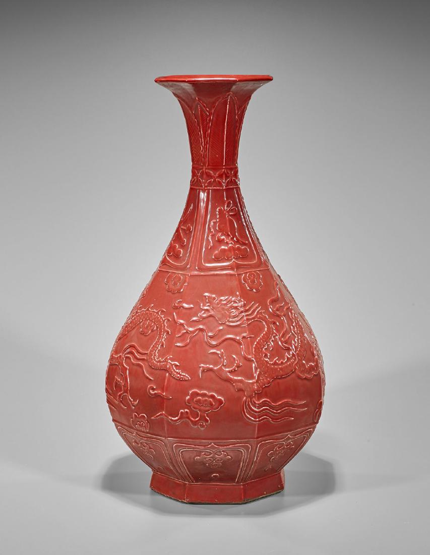 Tall Chinese Red Glazed Porcelain Vase: Tall Chinese red glazed porcelain vase; of faceted yuhuchunping form; with moulded dragons in relief, bordered by Buddhist emblems; H: 20 3/4" (approx.)