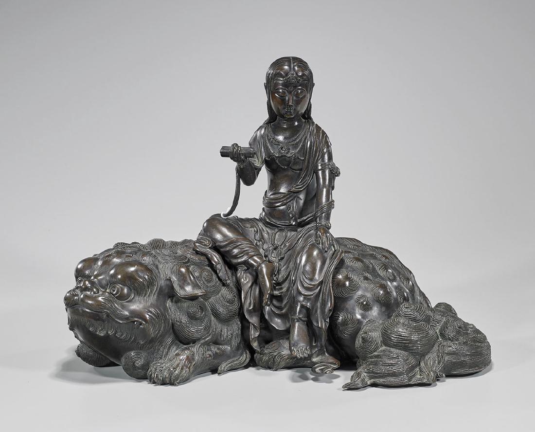 Antique Japanese Bronze Kannon & Shi-Shi: Antique Japanese bronze Kannon, seated atop a shi-shi; the Kannon swathed in robes, offering a scroll in right hand; the recumbent shi-shi with open, swirling eyes, incised with elaborate detail throu