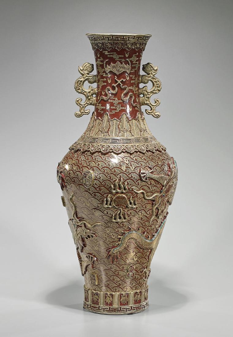 Tall Chinese Moulded Porcelain Vase: Tall Chinese porcelain vase; of baluster form; showing elaborate moulded gilt designs to body, including: bats; buddhist emblems; together with dragon and flaming pearl motifs, reserved on a red groun