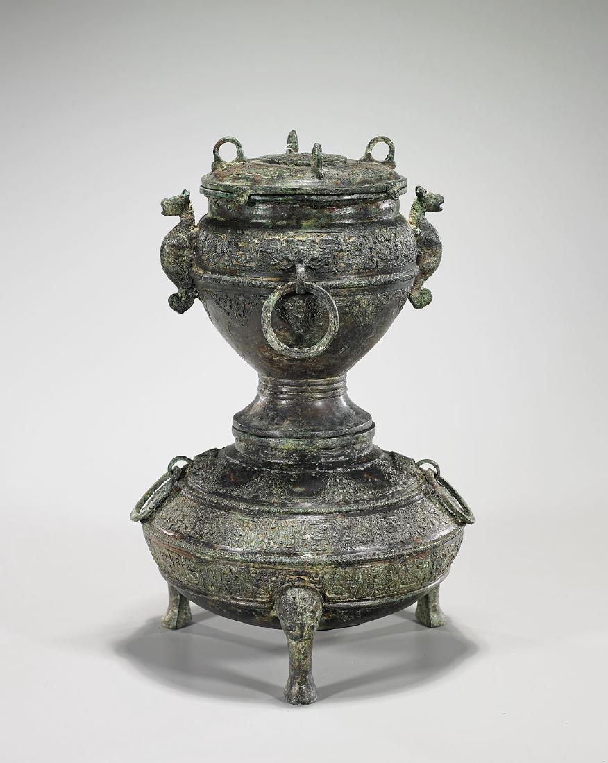 Chinese Archaistic Sectional Bronze Covered Vessel: Chinese archaistic sectional bronze covered vessel; set upon a tripod base with taotie-mask feet and animal form handles; four loops pending loose rings; showing several registers of scrolling archais