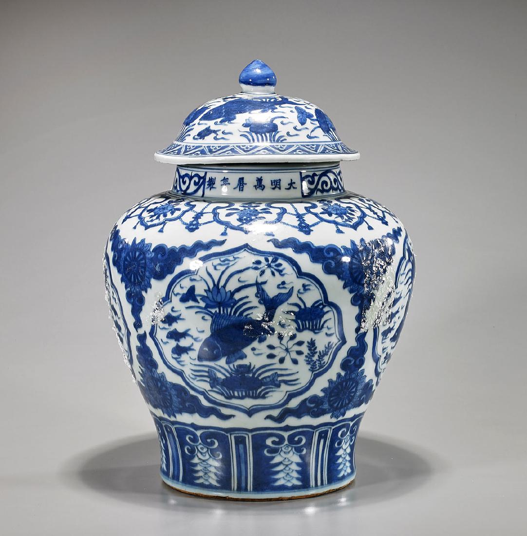 Chinese Blue & White Porcelain Covered Jar: Chinese Ming-style blue and white porcelain covered jar; of globular form; showing designs of fish amid pond flora to body and cover; with six-character Wanli mark to neck, but later; H: 16 1/2" &