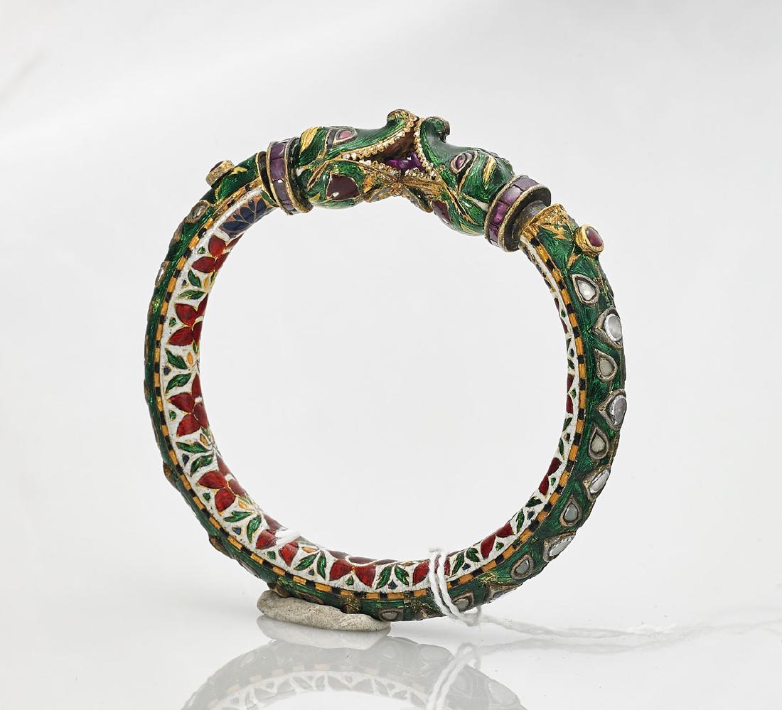 Mughal-Style Bracelet: Mughal-style bracelet; the green enameled shank inset with rose-cut glass and enameled foliate motifs; featuring two crocodile heads, with red 'jewel' accents to each terminal; hinged with red