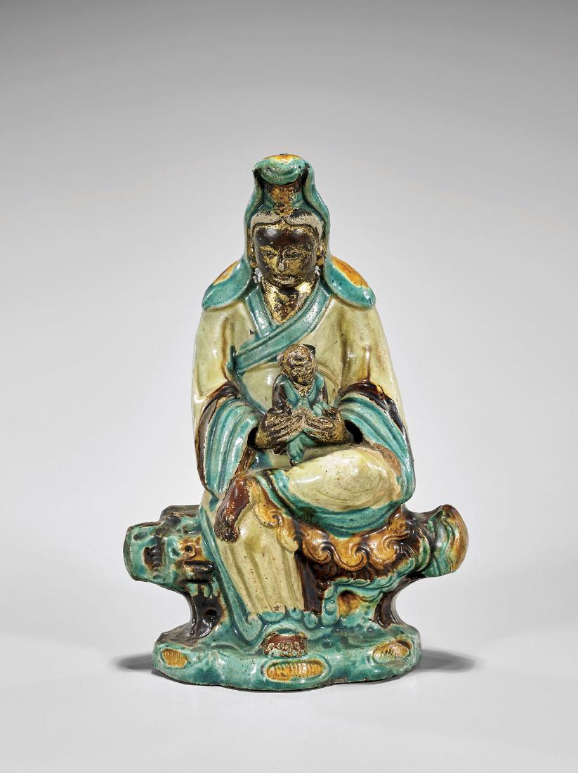 Ming Parcel-Gilt & Fahua Glazed Guanyin: Antique Chinese Ming Dynasty parcel-gilt and fahua glazed stoneware figure of Guanyin; seated in a position of ease, a boy in her lap, upon a base of cloud and wave motifs; H: 11" (approx.)