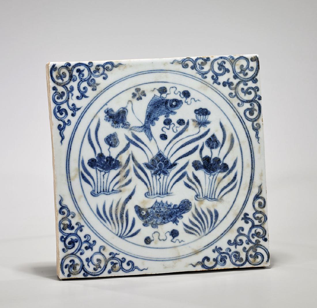 Yuan-Style Blue & White Porcelain 'Fish' Tile: Chinese Yuan-style blue and white porcelain tile; centering two fish swimming amid pond flora within concentric panels, reserved on a scrolling ground; H: 9 1/4" (approx.)