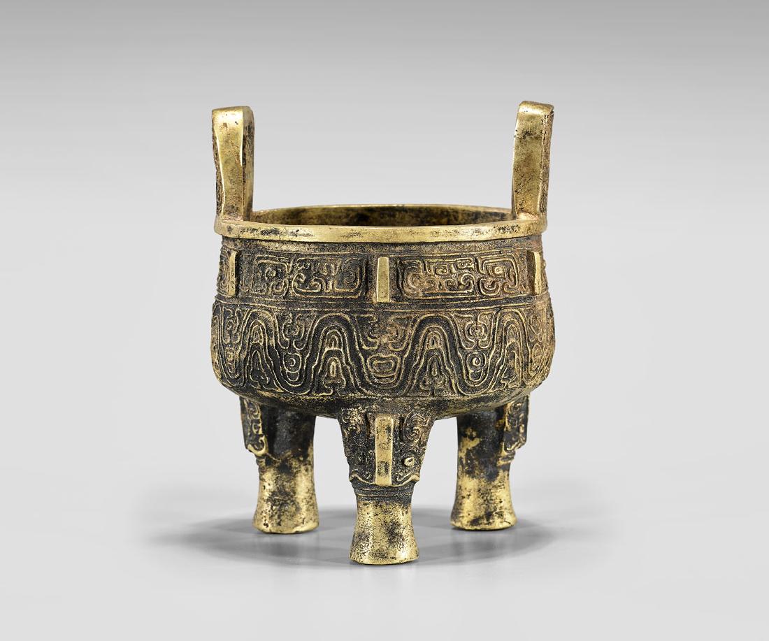 ARCHAISTIC GILT BRONZE TRIPOD CENSER: Archaistic Chinese gilt bronze tripod censer; with taotie relief decoration; H: 5 1/2"