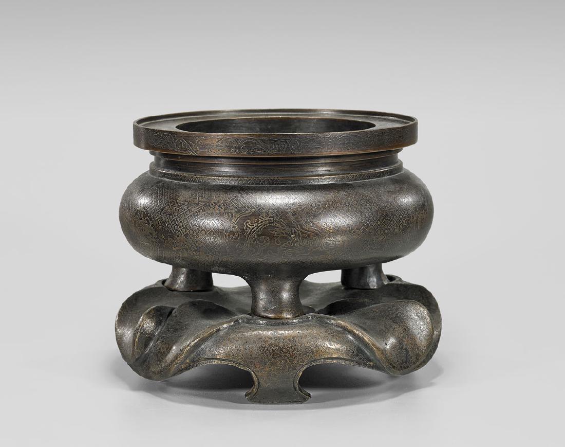 XUANDE-STYLE BRONZE TRIPOD CENSER: Chinese bronze tripod censer; of squat globular form, surmounted by a wide everted rim; overall decorated with figural scenes amid geometric patterning; matching foliate base; Xuande mark but 20th Cen