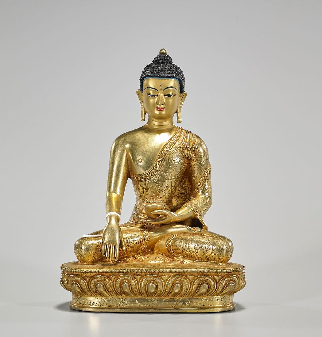 Nepalese Gilt Copper Shakyamuni Buddha: Nepalese gilt copper figure of Shakyamuni Buddha; showing a serene expression, with typical elongated ears and snail curled hair; hands in mudra, and holding a bowl; seated in a lotus position, atop a