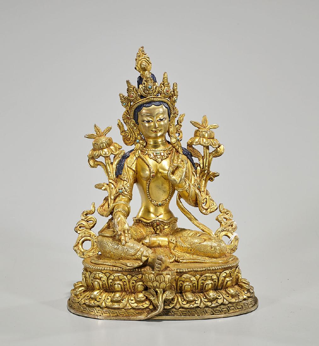 Nepalese Gilt Copper Seated Figure of Tara: Nepalese gilt copper figure of Tara; wearing elaborate jewelry and crown, set before the flaming ushnisha; hands in mudra, arms framed by blooming flowers; seated atop a double lotus base; H: 9 1/4