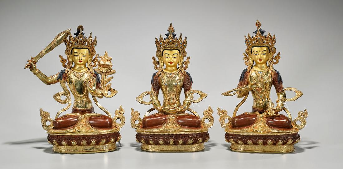 Set of Three Nepalese Gilt & Polychrome Copper Figures: Set of three Nepalese gilt and polychrome copper figures of Manjushri; each showing a serene expression, wearing flowing garlands and headdress, with inlaid 'jewels'; hands gesturing, and hold