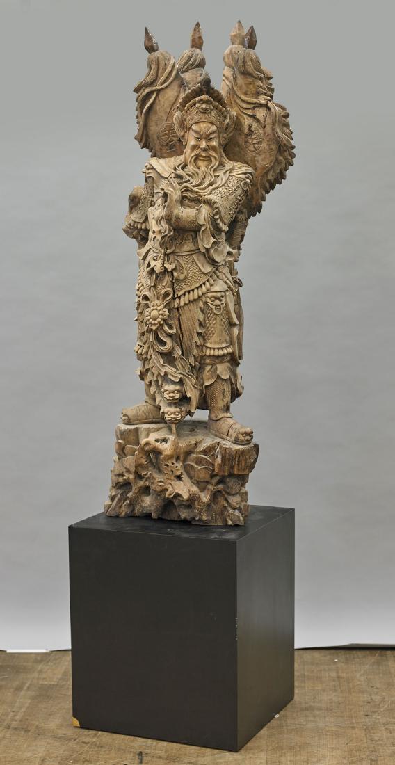 Massive Chinese Carved Wood Figure of Guandi: Massive Chinese carved wood figure of Guandi; wearing an elaborate dragon-motif armor and crown; hands gesturing, and holding his beard; standing before four flags, atop a rockery form base; H: 58 3/4