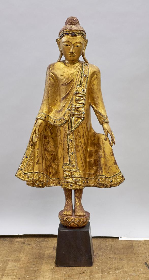 Antique Burmese Gilt Carved Wood Standing Buddha: Antique Burmese gilt carved wood Buddha; embellished with 'jewels'; standing atop a lotus base; H: 40" (approx.); wood stand