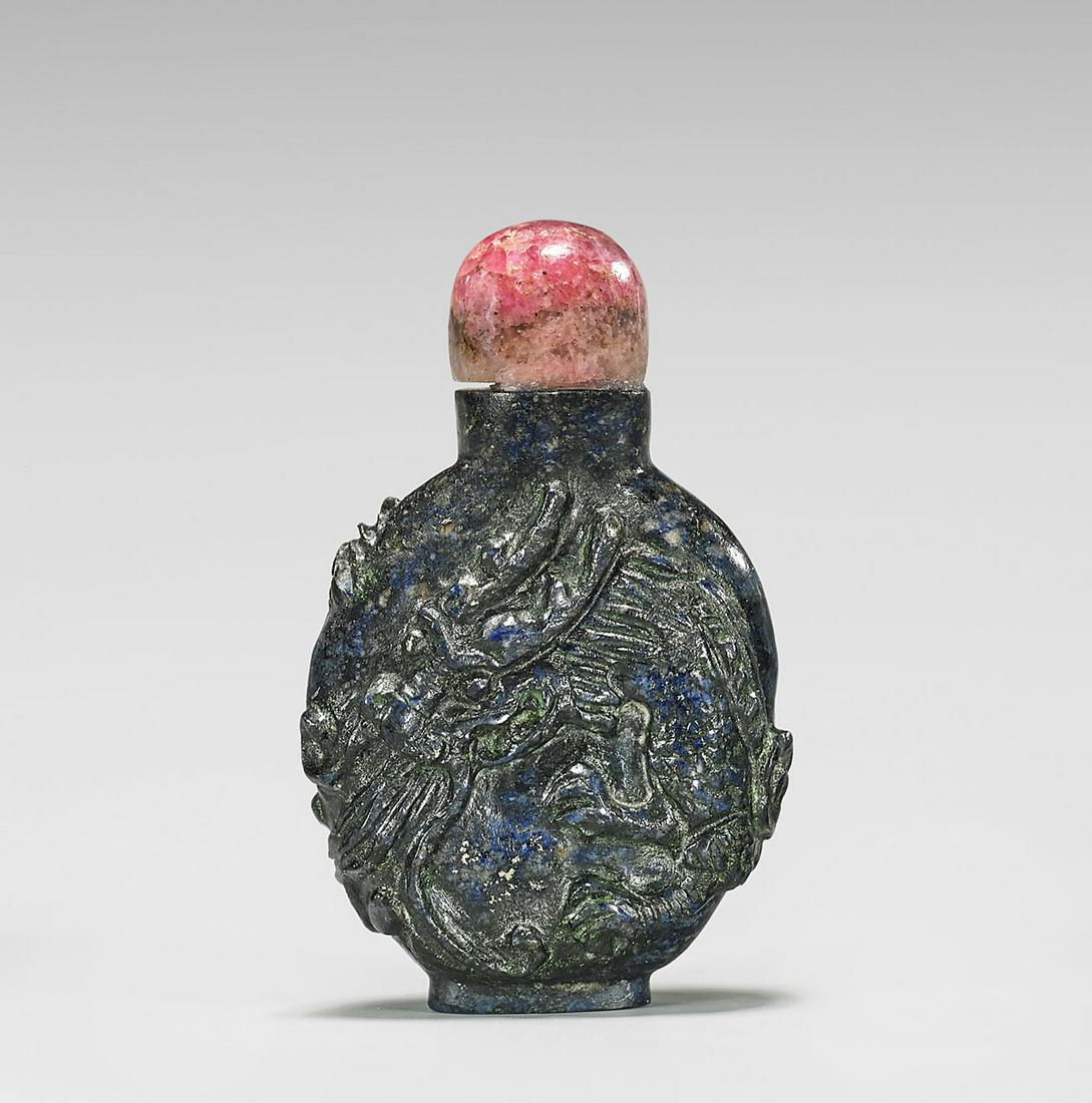 OLD LAPIS LAZULI SNUFF BOTTLE: Old Chinese dark lapis lazuli snuff bottle; the flattened ovoid form carved with a writhing dragon wrapped around the entirety; with rhodonite stopper; Provenance: the Estate of Ted Adameck; H: 2 1/4&