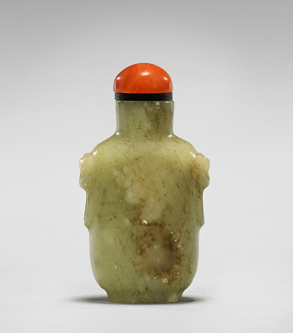 Antique Chinese Carved Jade Snuff Bottle: Antique Chinese carved celadon jade snuff bottle; carved with mock-ring mask handles, the jade showing "mutton-fat" suffusions and tan veining; with carnelian agate stopper; H: 2 1/2"