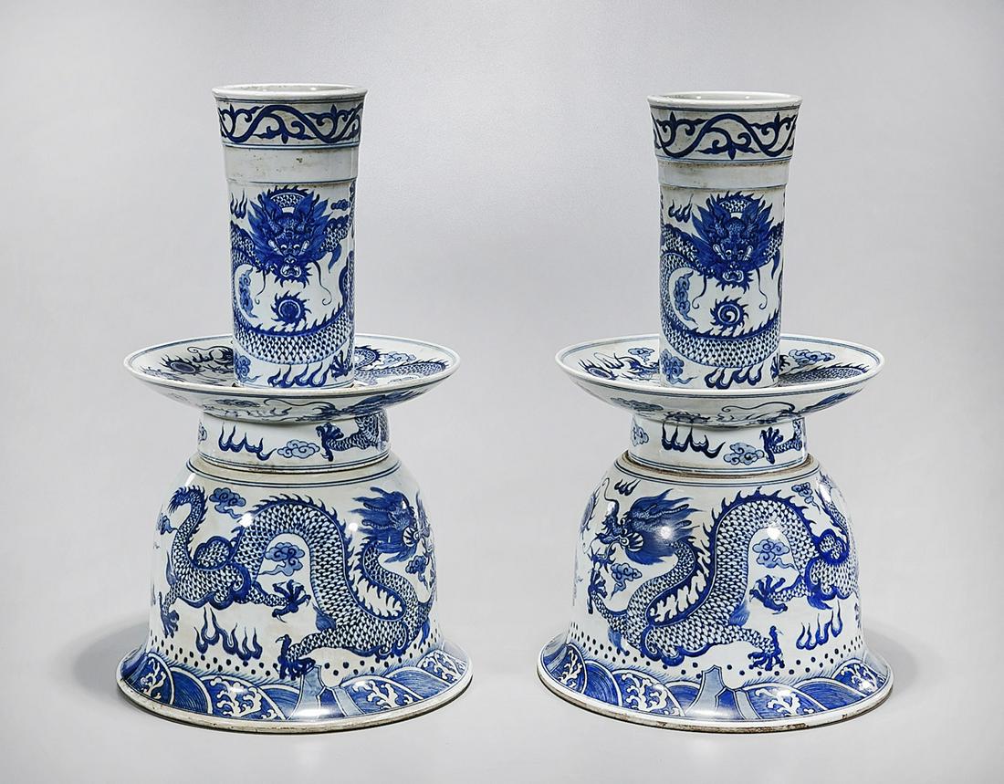 Pair Chinese Blue and White Porcelain Candlesticks: Pair of Chinese blue and white porcelain bell-shaped candlesticks; with dragons chasing pearls motif; 19" x 11" (each, approx.) Condition: repair to one; wear, frits, pits, minor loss