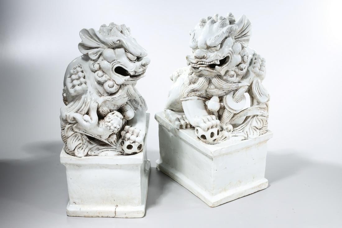 Pair Chinese White Glazed Porcelain Fo Lions: Pair of Chinese white glazed porcelain fo lions; 19 1/2" x 8" x 14" (each, approx.) Condition: wear, minor loss, flaws, small hairline/firing crack