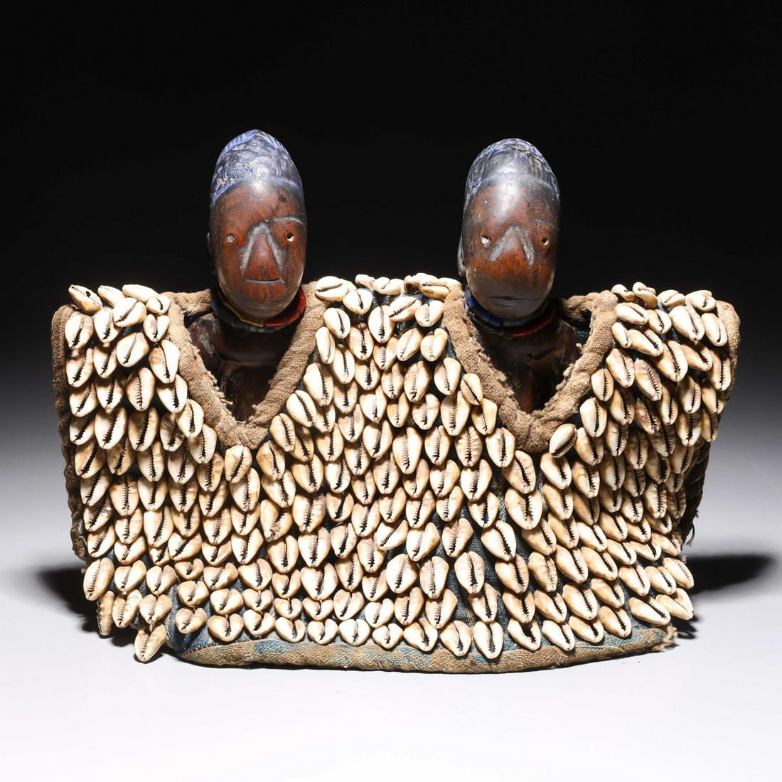 Pair of Ibeji Figures with Cowrie Shell Cloth Covering: Pair of carved wood Nigerian Ibeji figures with cowrie shell cloth covering, with certificate of authenticity from the Rodeo Collection of Beverley Hills, CA; H 8 3/4" x W 11 3/4" x D 4" (approx.) Pro