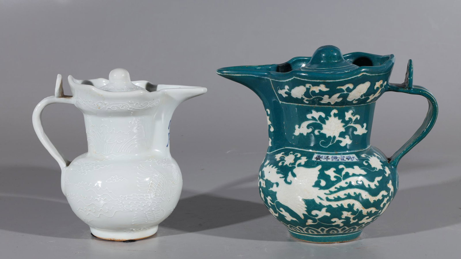 Two Chinese Glazed Porcelain Ewers: Two Chinese glazed porcelain ewers including one white glazed ewer with phoenix and dragons chasing flaming pearl on body, two character mark beneath spout, and teal glazed ewer with phoenix and flowe