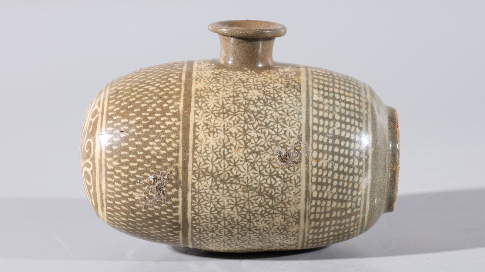 Korean Celadon Glazed Wine Vessel: Korean celadon glazed barrel form white wine vessel with all over geometric designs; chip and large crack to body; H 7 1/2" x W 5"