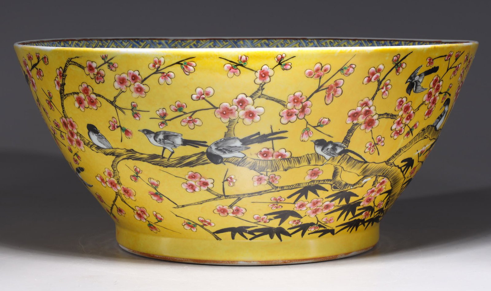Large Chinese Enameled Porcelain Bowl: Large Chinese yellow ground famille rose enameled porcelain bowl with birds and cherry blossoms to exterior, four-character coral red mark to base; as-is condition with large cracks and repairs; H 7" 