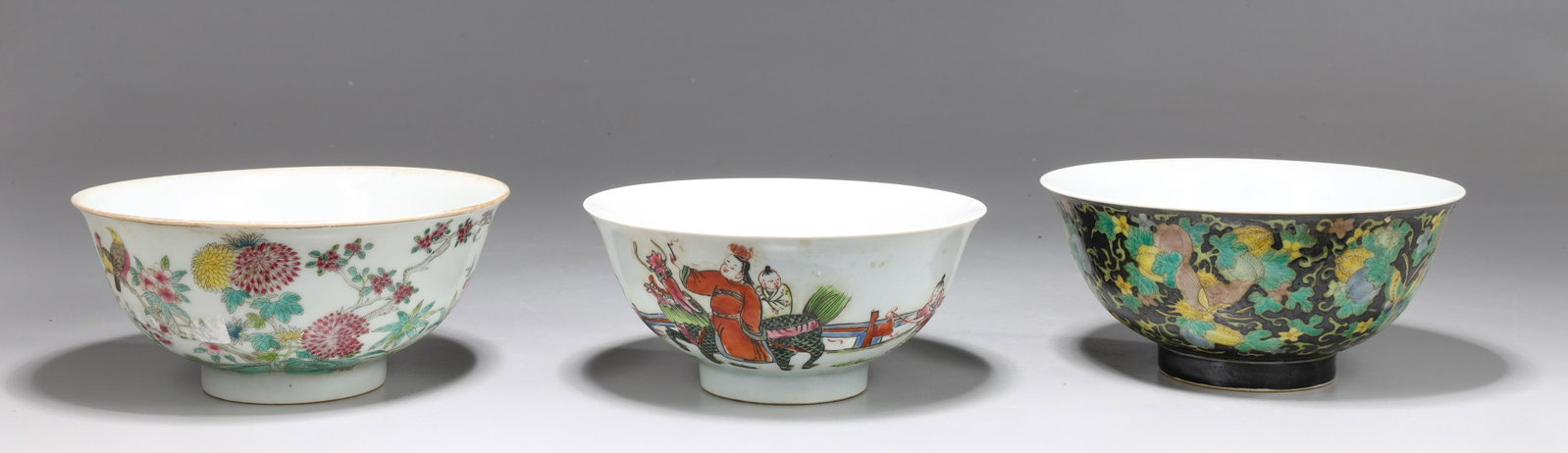 Three Chinese Enameled Porcelain Bowls: Three Chinese enameled porcelain bowls including bowl with white interior, red central design of bats, exterior with adult atop qilin and children around above raised foot, coral red mark to base; tog