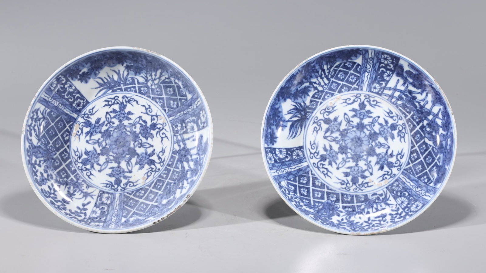 Pair of Chinese Blue & White Porcelain Plates: Pair of Chinese blue and white porcelain plates with intricate floral patterns to surface and exterior; some wear and losses; H 1 1/2" x D 8 1/2" (approx.)
