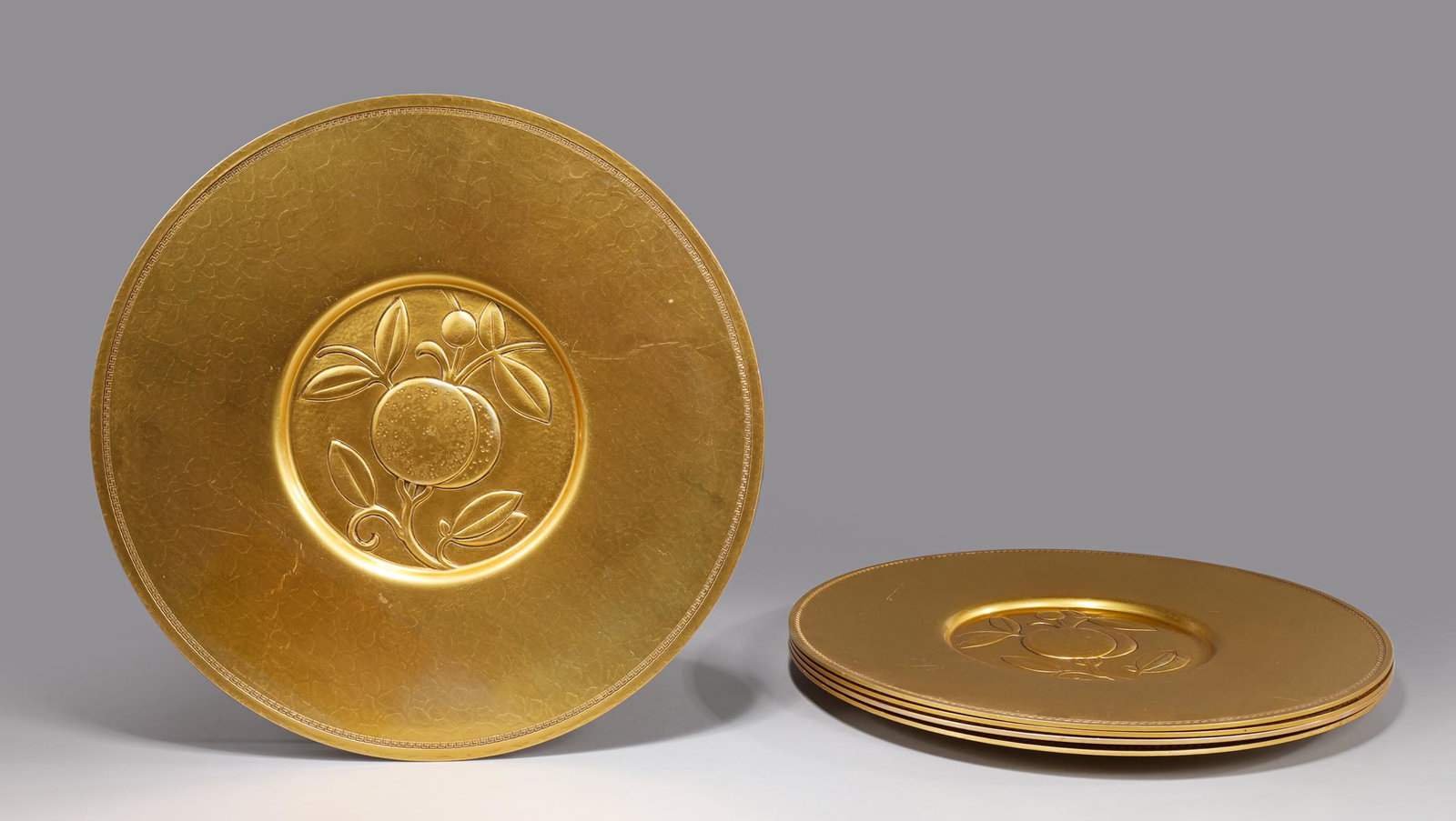 Group of Five Beaumet Charger Plates by Sterling Bronze Co.: Group of five Beaumet charger plates in gilt finish by Sterling Bronze Co., New York: fruit motif, light surface soiling, light abrasion on verso, light age wear; L 12" W 12" H 1/2" (Approx.)