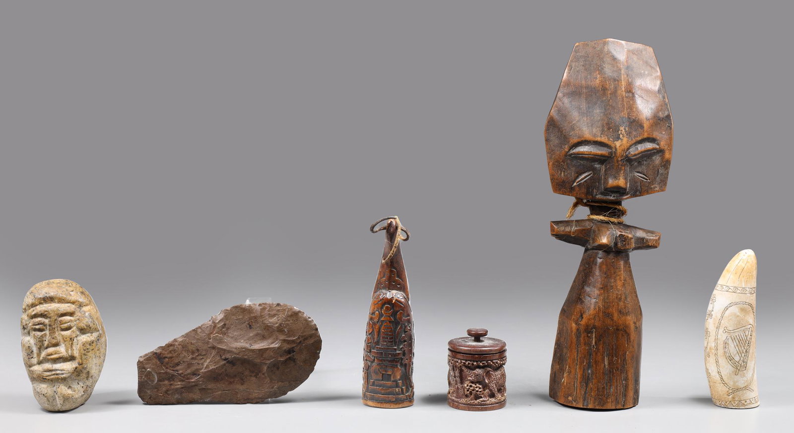Group of Six Carved Stone and Wood Ethnographic Collection: Group of six carved mixed stone and wood ethnographic collection, including, marble what tooth replica, African trinket box, flint tool, figural stone, and figural totem; as is condition, moderate age