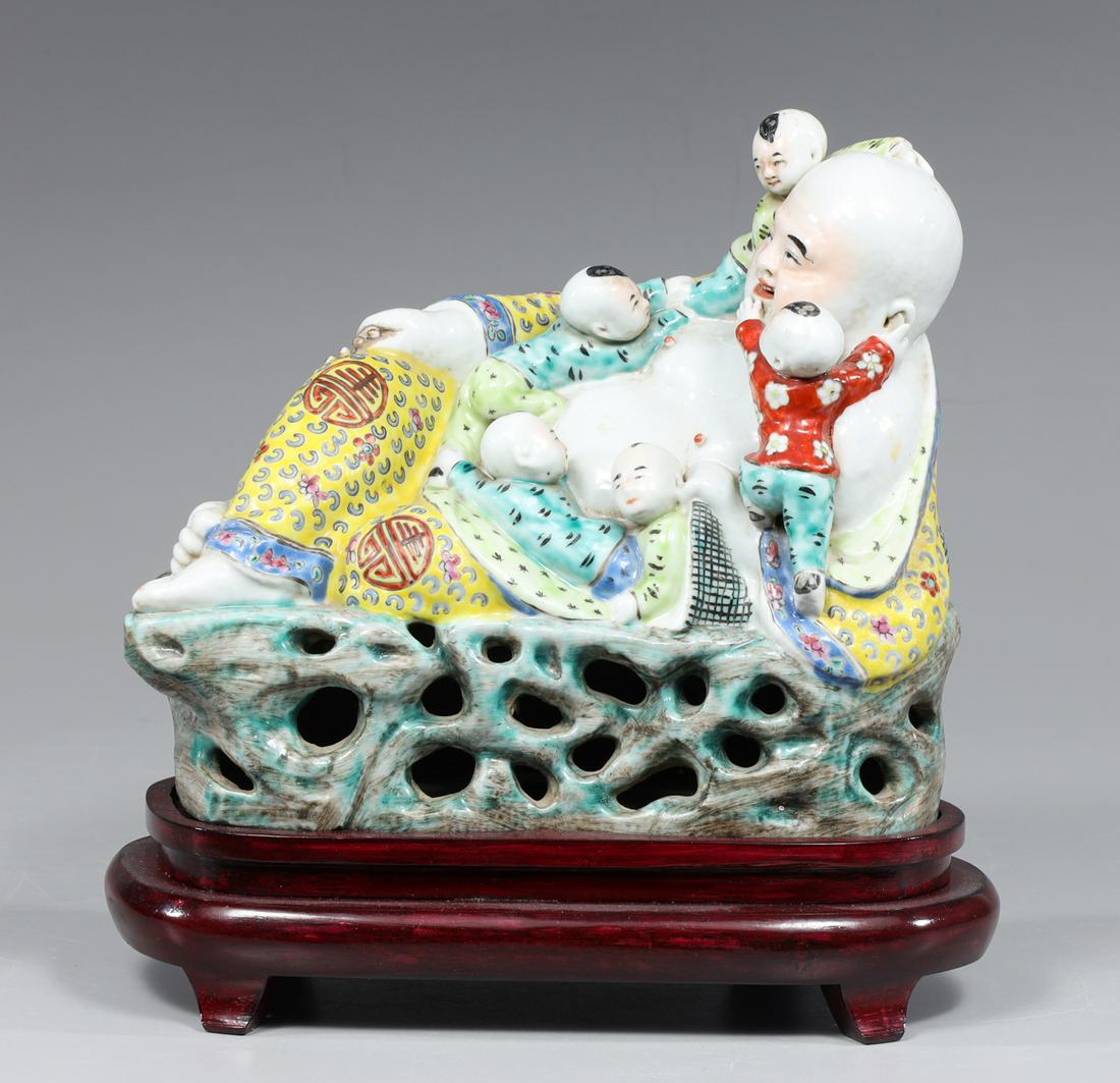 Antique Chinese Porcelain Reclining Buddhi w/ Children: Antique Chinese porcelain reclining Buddhi with five children, the Buddhi dressed in elaborate robs reclining atop a rocky outcrop with openwork to the front, accompanied with a wood stand and certifi
