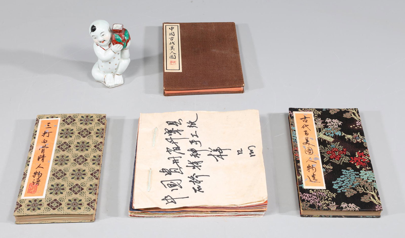 Group of Five Chinese Ephemera and Porcelain Collection: Group of five Chinese portrait books, porcelain figure, and pressed paper book; overall good condition, age wear, surface wear, surface soiling; largest H 6" (Approx.)