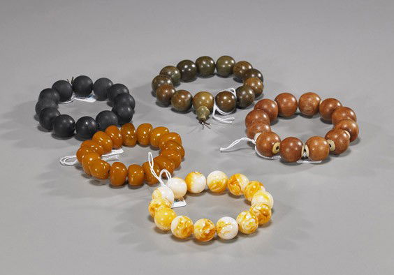 Five Various Chinese Bead Bracelets: Five Various Chinese Bead BraceletsGroup of five various Chinese bead bracelets, including: round wood with bone inserts; round wood with incised Guanyin and character designs; yellow amber-like pebbl