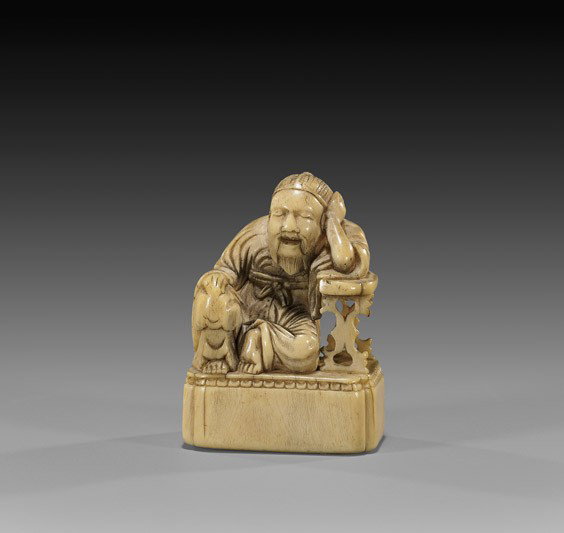 ANTIQUE IVORY NETSUKE: Scholar & Table: ANTIQUE IVORY NETSUKE: Scholar & Table Antique and well carved, ivory netsuke: of a seated scholar, leaning against a table; all set on a raised base; 19th Century, unsigned